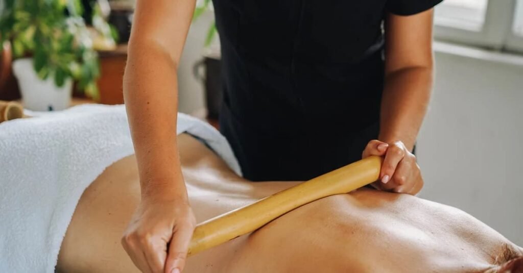 Terapeuta aplicando massagem com bastão em paciente deitado