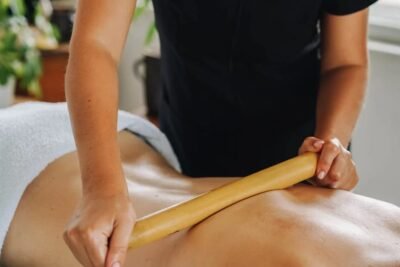 Terapeuta aplicando massagem com bastão em paciente deitado